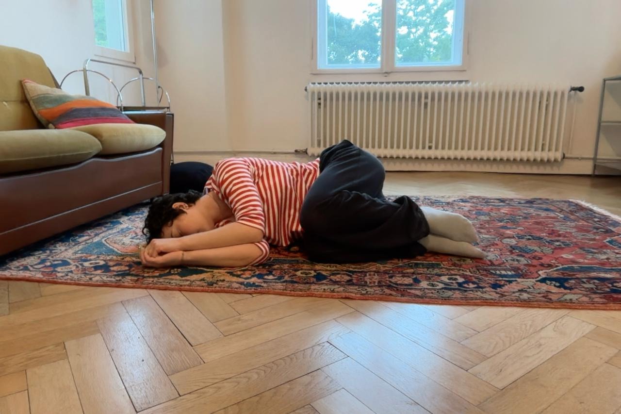 Louella à 20 ans en position fœtale sur un tapis persan, appartement berlinois